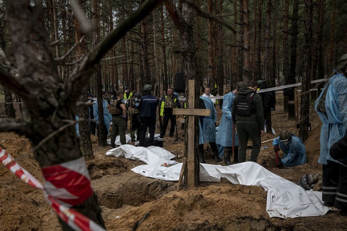 Ukrainian investigators work at a mass grave site in a pine forest near Izium, a city recently liberated from Russian control, on Friday, Sept. 16, 2022. (Nicole Tung/The New York Times)